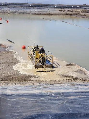 Operator on a hydraulic dredge removing sludge from a lined lagoon