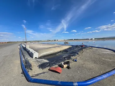 Dewatering tube and transfer hose beside a lagoon